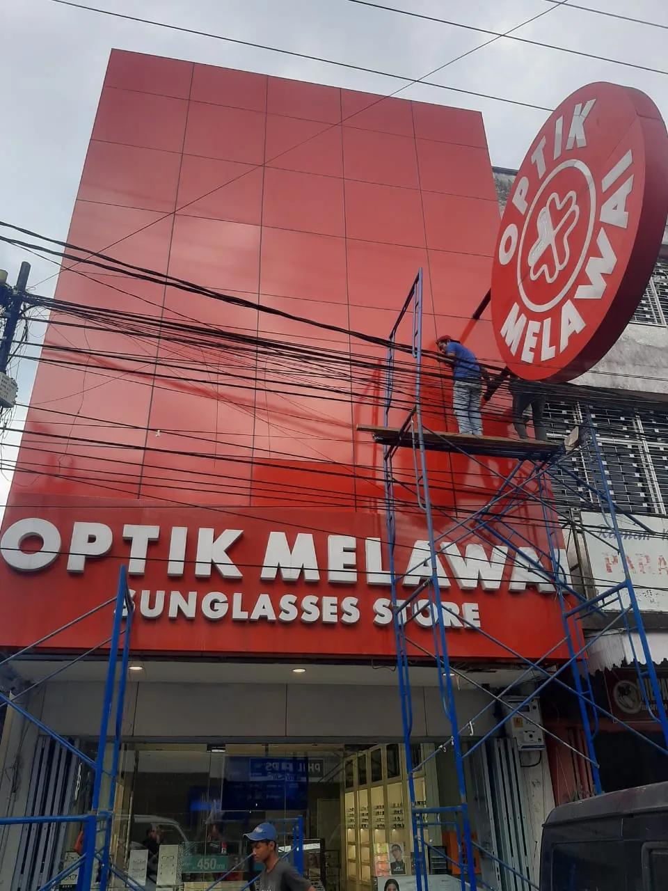 Pemasangan fasad ACP merah untuk toko Optik Melawai